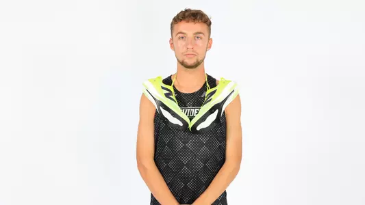 Sam Hodgson posing with his spikes wrapped around his shoulders during a photo shoot 