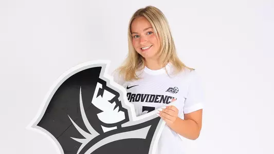 Kenzie Ellis Holding Friar Head Logo Posing