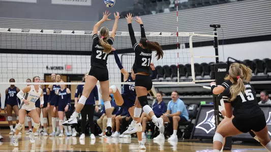 Kaia Easterbrook and Sophia Adkins block against URI