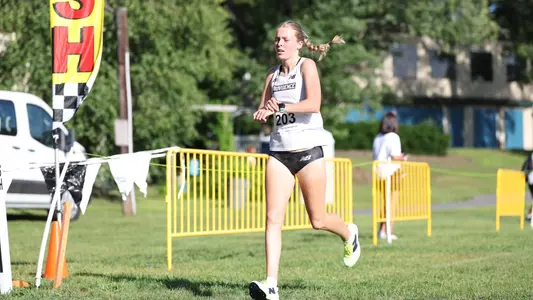 Women's cross country runner Gabby Schmidt crossing the finish line at the Friar Invitational