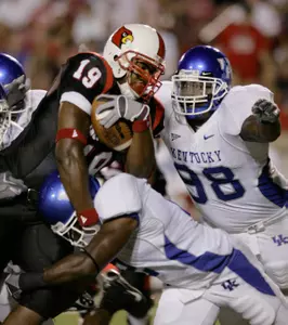 Louisville running back Michael Bush is tackled by Kentucky's Marcus McClinton, bottom, as McClinton's teammate Myron Pryor (98) moves in to help during the first half of their college football game Sunday, Sept. 3, 2006, in Louisville, Ky. (AP Photo/Ed Reinke)