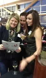 Alumnae Michelle Hess Husted (left) and 2012 Alumna of the Year Kelly Gillooly Watts look over memorabilia from Kelly's setting career as her husband, Jamie, looks on.