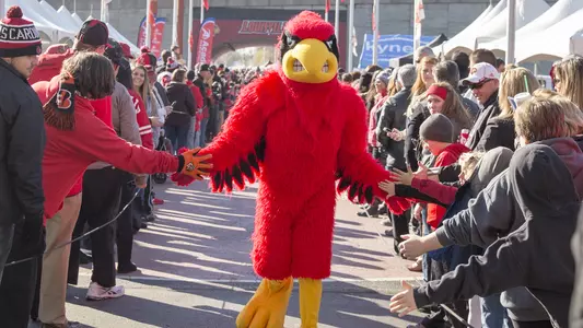 Louisville's mascot Louie slaps hands with fans prior to a football game during CardMarch. | Fan Center