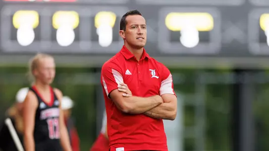Field hockey assistant coach Will Holt coaches from the sideline