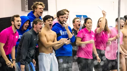 Swim team cheering on those in the pool.