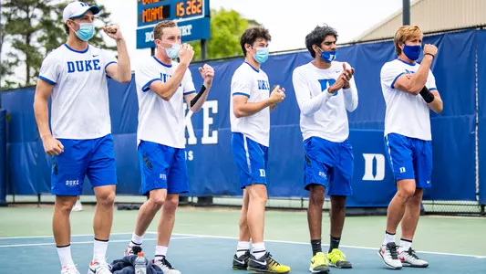 Men's tennis players cheer on their teammates during Duke's match with Miami