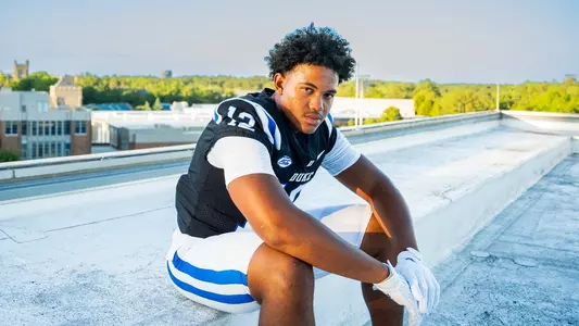 Duke's Bryce Davis sits outside and poses for a photo in a black football jersey and white pants.
