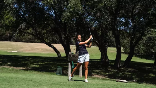 Ella Forss follows through on a tee shot wearing a black polo