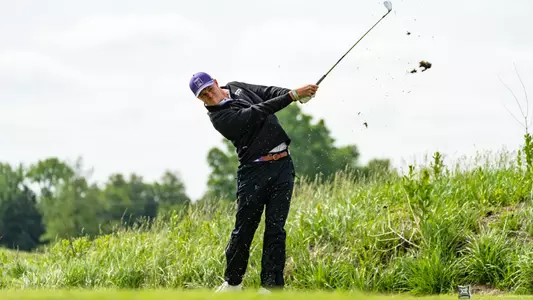 Lewis Wright hits an iron as grass falls from the end of the club.