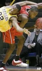 Michigan's J.C. Mathis is bent over backwards over Julius Hodge trying to get to a rebound in the second half.