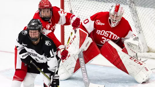 Abbey Stanley battles with a Providence skater in front of goaltender Corinne Schroeder
