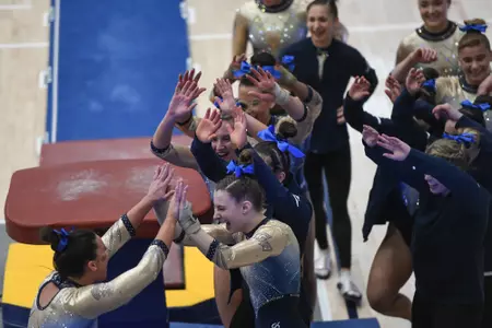 Crasa high fives teammates after competing on vault.