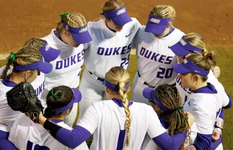 JMU softball huddles before play.
