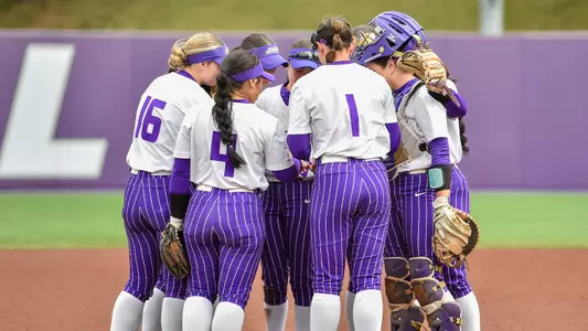 Softball gathers together in a team huddle. 