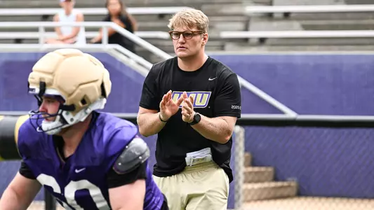 Cole Holtz coaches the offensive line during a drill at a JMU football practice