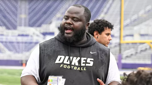 Kali James speaks to the defensive line during a JMU football practice