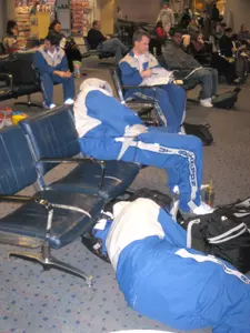 Head coach Scott Cross looks through scouting material as team members rest during a flight delay at the Dallas-Fort Worth Airport on Friday afternoon.