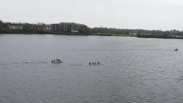 A 1920 x 1080 aerial image depicting an Eastern Michigan University women's fours boat on the stunning waters of the EMU Rowing Course at Ford Lake