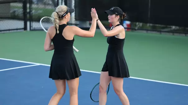 Flora Eidson and Allison Root of the women's tennis team celebrate during their match against Assumption University