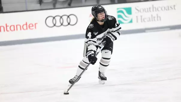 Women's ice hockey player Josie Lang skating up ice with the puck
