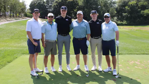 Men's hockey players Tomas Machu and Kale McCallum pose with participants at the annual men's hockey vision cup golf tournament.