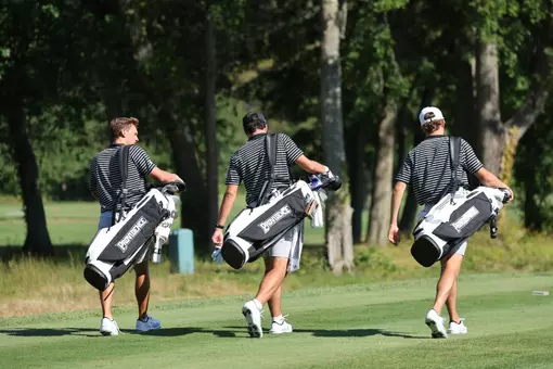 Men's golf players Joe Halferty, Callan Fahey and Will Spring walking up the fairway with their golf bags
