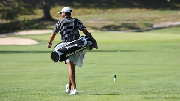 Men's golfer Campbell Skelly walking up the fairway with his bag
