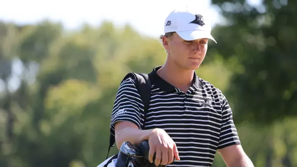 Men's golfer Evan Buddenhagen walking with his bag
