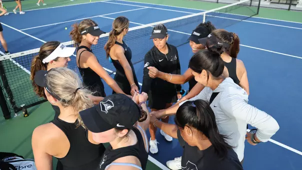 Women's Tennis team huddles up prior to a match against Assumption University
