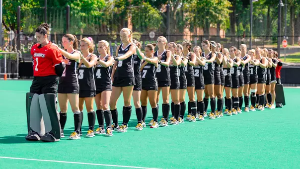 The Providence College Field Hockey team stands in a single-file line on the field during the playing of the National Anthem.
