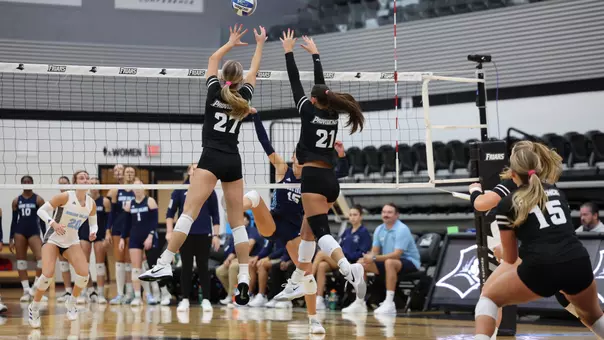 Kaia Easterbrook and Sophia Adkins block against URI