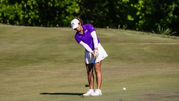 Kirstin Angosta chips off the fringe of the green wearing a purple shirt and white sleeves