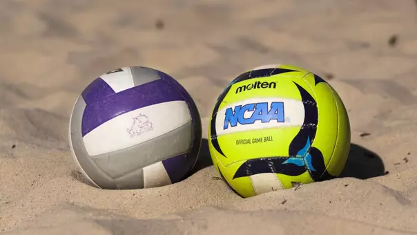 TCU and NCAA volleyball placed next to each other on a sand court