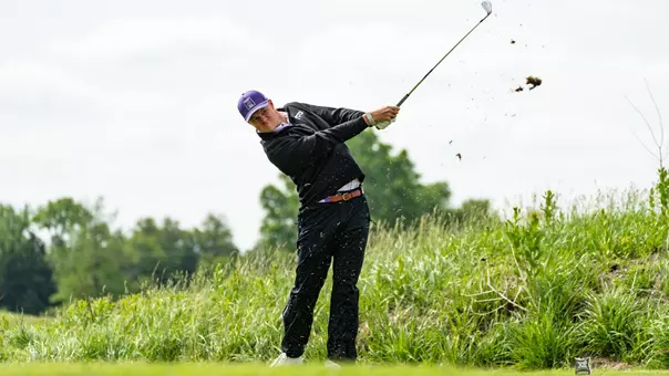 Lewis Wright hits an iron as grass falls from the end of the club.