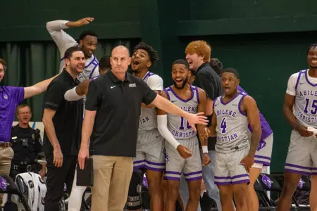 Wildcats bench celebrates a dunk from Tobias Cameron in a win over Schreiner