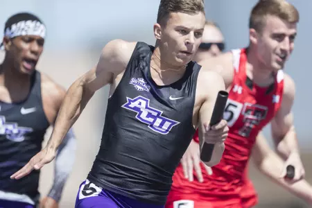Jack Marshall carries a relay baton vs. Texas Tech