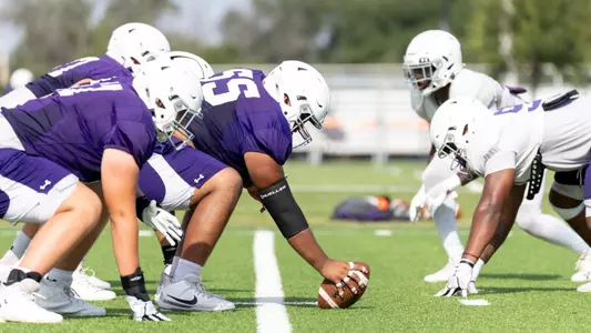 ACU football offensive and defensive linemen line up at practice in August 2025