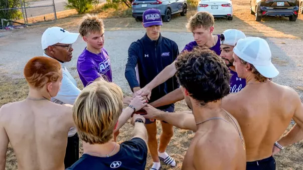 Cross country head coach Wayne Angel and his men's team put heads together after the season's first practice in August 2026.