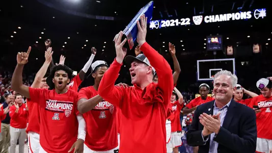 Tommy Lloyd raises up the Pac-12 championship trophy at McKale Center