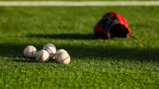 Stock image of baseballs and a hat on grass