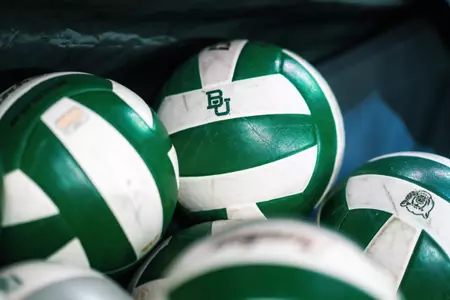A BU branded volleyball rests in a ball cart during warmups.