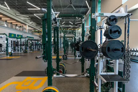 Interior photos of the Fudge Football Development Center weight room with racks of weights, dumbbells, squat racks, etc.