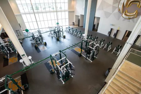 Interior photos of the Fudge Football Development Center weight room with racks of weights, dumbbells, squat racks, etc.