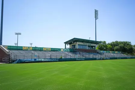 Facility photos of Betty Lou Mays Field; updated signage in 2026 features 2025 Sweet 16 and Tyler Isgrig All-America accolades
