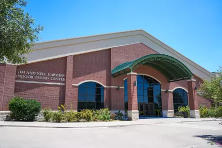 Exterior and interior photo of Hawkins Indoor Tennis Center in 2026, showcasing the outside entrance, courts, lobby and seating areas