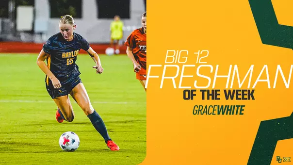 Graphic announcing Grace White as Big 12 Freshman of the Week. On the left, White, a Baylor soccer player in a navy No. 15 jersey, dribbles a soccer ball on the field with an opposing player in orange nearby. On the right, bold white and black text reads "Big 12 Freshman of the Week" with "Grace White" beneath it in teal and white lettering, set against a gold background with dark green geometric accents and the Baylor and Big 12 logos in the bottom corner.