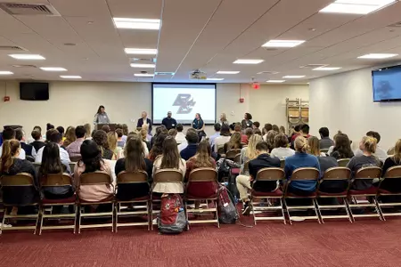 Current Eagle seniors listen to alums speak about job hunting.