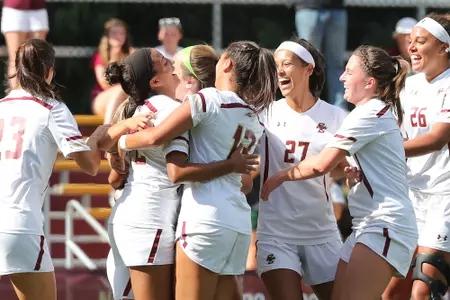 Group of women's soccer players celebrating a goal vs. UNH
