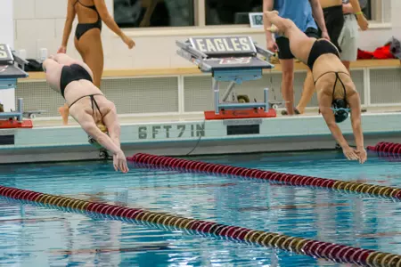 Women's swimmers dive into the pool at the Connell Center