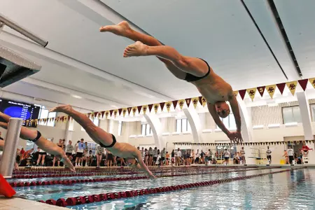 Men's swimmers dive into the pool at the Connell Center.